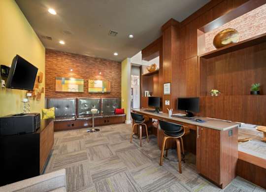A room with a brick wall and a desk with a computer.