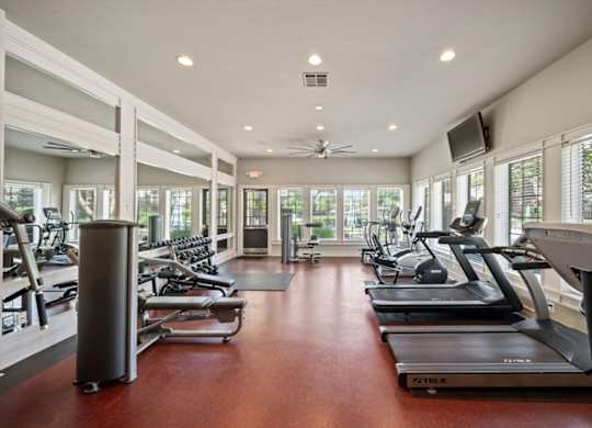 A gym with treadmills, exercise bikes, and a television.