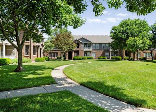 A tree-lined walkway leads to a building.