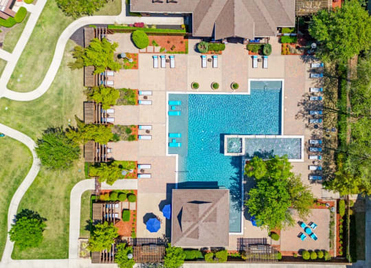 arial view of a swimming pool in the middle of a house with trees