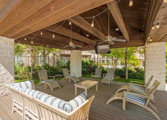 a covered patio with chairs and a tv