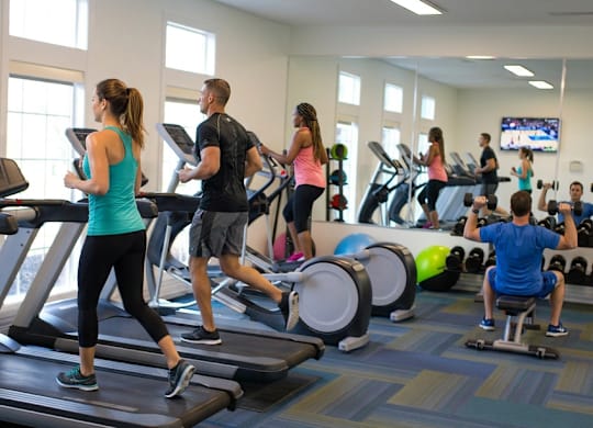 A group of people are exercising on treadmills in a gym.
