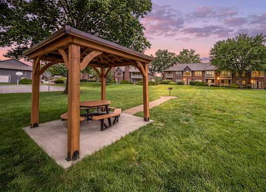 Covered picnic pavilion at twilight overlooking landscaped grounds and apartment homes.