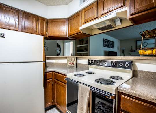 A white refrigerator is in a kitchen with wooden cabinets.
