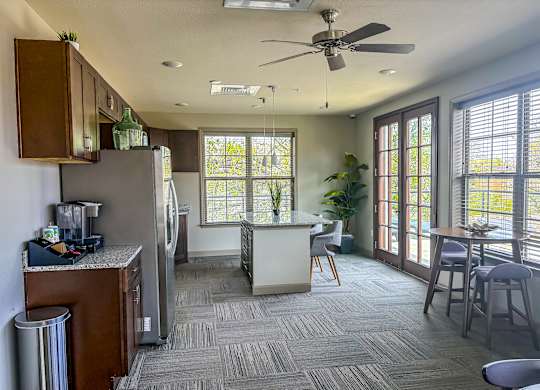 Rooftop lounge at The Dorset Apartments with coffee station, dining tables, and access to outdoor terrace through French doors.