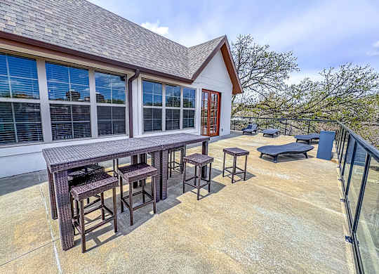 Rooftop terrace at The Dorset Apartments featuring dining tables, lounge chairs, and scenic city views.