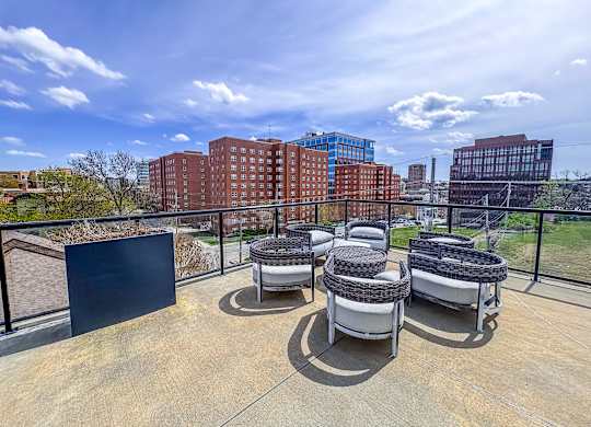 Skyline view from rooftop terrace at The Dorset Apartments with outdoor circular lounge seating and glass railing.