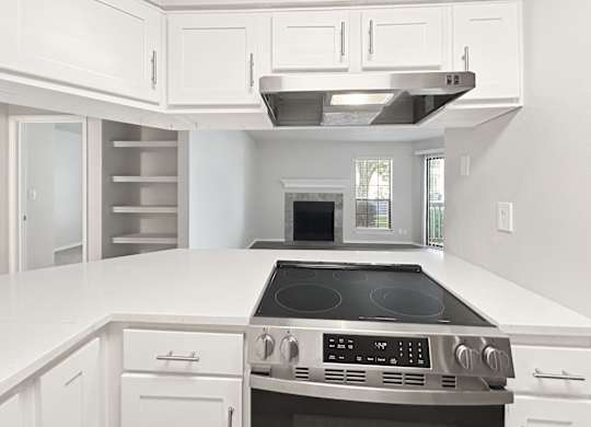 A modern kitchen with white cabinets and a stainless steel stove top.