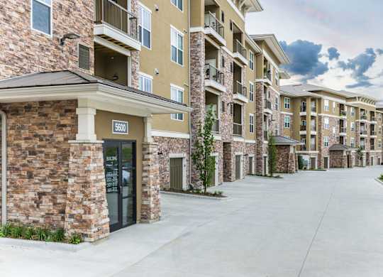 Apartment complex with a stone building and a car parked in front. at Residences at Prairiefire Apartment Homes, Overland Park, Kansas