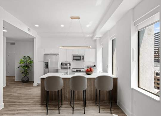 A modern kitchen with a bar stool and a dining table.
