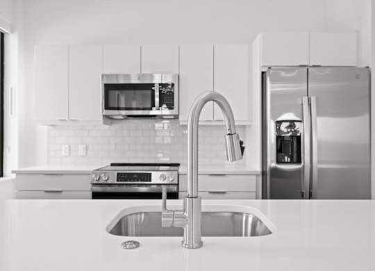 A modern kitchen with a stainless steel refrigerator and a sink.