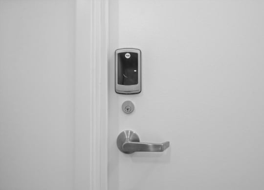 A white door with a silver handle and a keypad lock.