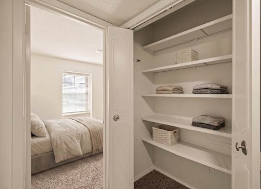 Spacious closet with built-in shelving and hanging space located next to a bedroom at Louisburg Square Apartments in Overland Park, KS.