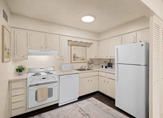 Kitchen with white cabinets, electric range, dishwasher, refrigerator, and laminate countertops at Louisburg Square Apartments in Overland Park, KS.