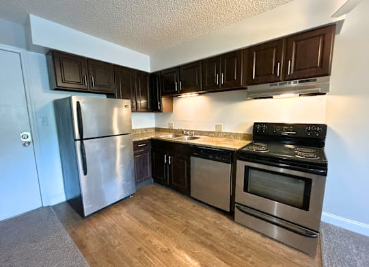 Classic Studio - Kitchen with a stainless steel refrigerator, black oven, and wooden cabinets.
