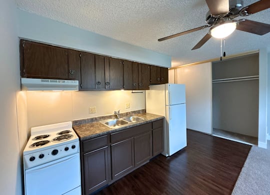 Classic Studio - Kitchen with white appliances and dark wood cabinets.