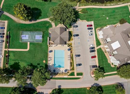 Overhead drone image of the swimming pool, basketball court, clubhouse, and surrounding apartment homes at Millcreek Woods.