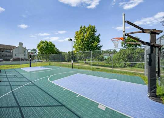 Fenced outdoor basketball court with a well-maintained playing surface at Millcreek Woods Apartment Homes.