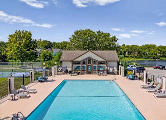 Outdoor swimming pool with lounge seating and lake views at Millcreek Woods Apartment Homes.