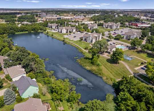 Drone view of the community lake, residential buildings, walking paths, and amenities.