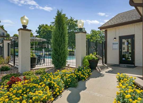 Welcoming leasing office entrance with landscaped flower beds and nearby community pool views.