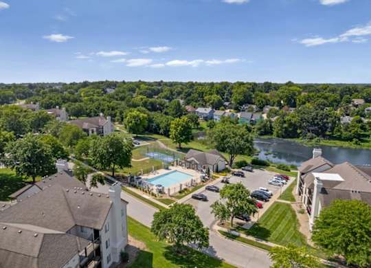 Drone view featuring the pool, basketball court, clubhouse, and surrounding apartment homes.