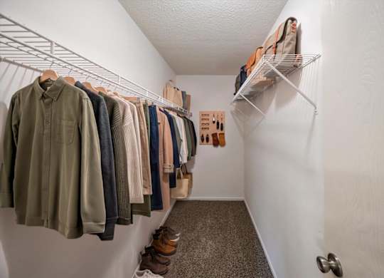 Extended walk-in closet with hanging rods, shelving, and additional storage space.