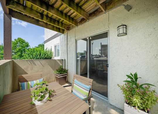 Covered patio featuring outdoor dining furniture, decorative planters, and sliding glass door access.