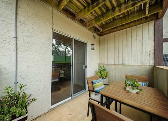 Spacious covered patio with outdoor seating, wood ceiling accents, and access to the apartment interior.
