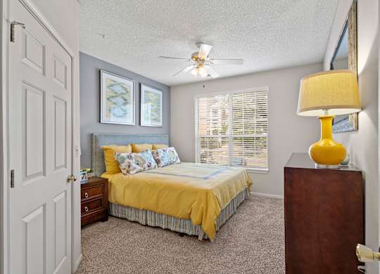 A bedroom with a bed, dresser, and ceiling fan.