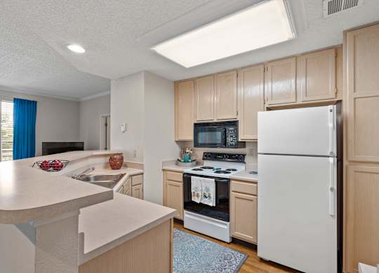 A kitchen with a white refrigerator and white cabinets.