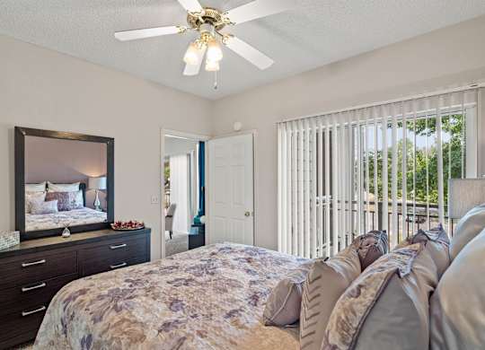A bedroom with a ceiling fan and sliding glass patio door.