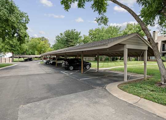 A parking lot with a covered parking area and a tree.