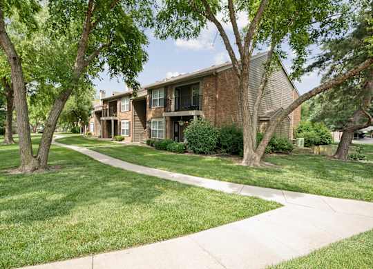 A tree-lined residential street with a house on the right.