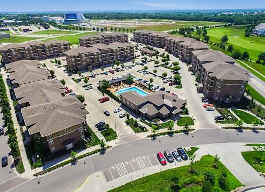 A large apartment complex with a pool in the middle of the courtyard. at Residences at Prairiefire Apartment Homes, Kansas