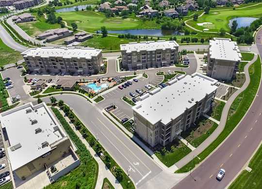A large apartment complex with a pool and a golf course in the background. at Residences at Prairiefire Apartment Homes, Kansas, 66223
