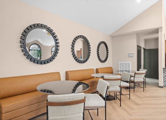 A living room with a brown sofa, a glass table, and three round mirrors on the wall.