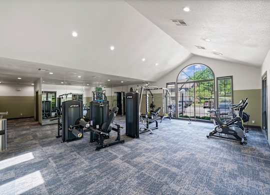 A spacious gym with a variety of equipment and a large window.