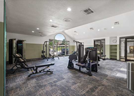 A gym with a variety of equipment including treadmills, weights, and exercise machines.