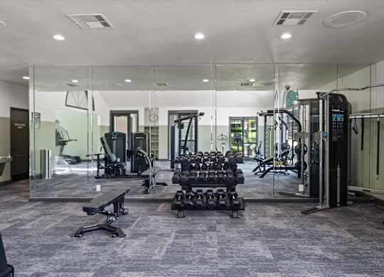 A gym with a variety of equipment including treadmills, weights, and exercise machines.