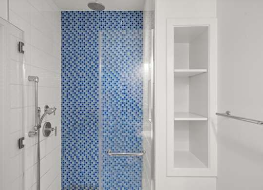 A white bathroom with a blue tiled shower.