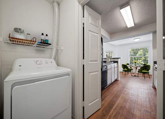 In-unit laundry area with dryer and shelving at Stonebriar Apartments in Overland Park Kansas