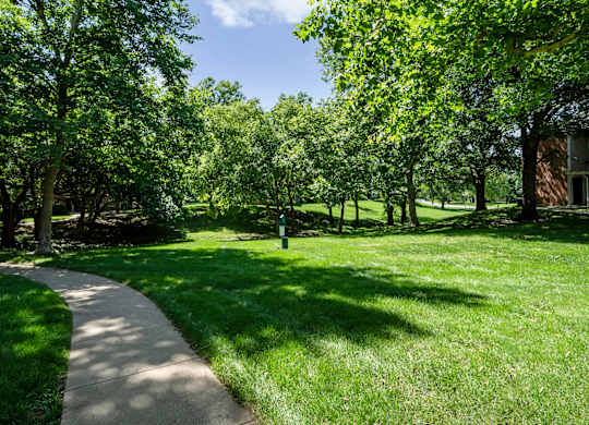 Landscaped green space with trees and walking path at Stonebriar Apartments in Overland Park KS