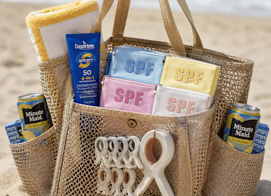 A straw bag filled with sunscreen and other beach items.