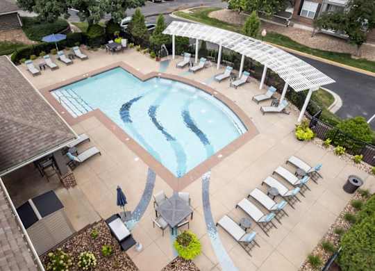 Overhead view of the resort-style swimming pool, shaded seating area, and pool deck at The Claremont Apartments in Overland Park, KS.
