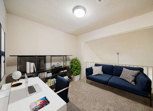 A blue couch sits in a living room with a white table and a plant.