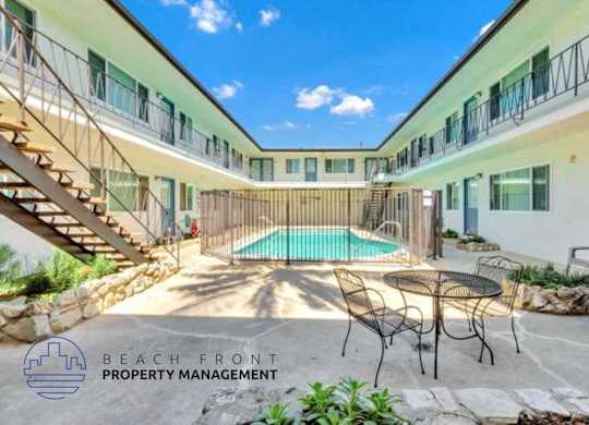 a courtyard with a pool and chairs and a table