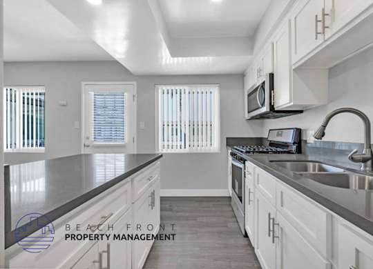 A kitchen with white cabinets and a stainless steel sink.