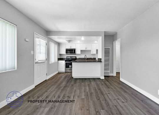 an open kitchen and living room with white walls and wood floors