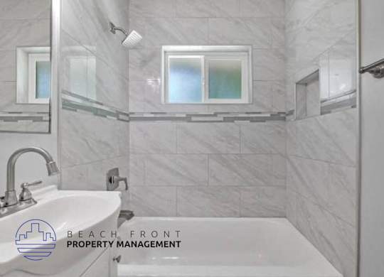 A bathroom with a marble tile wall and a white sink.